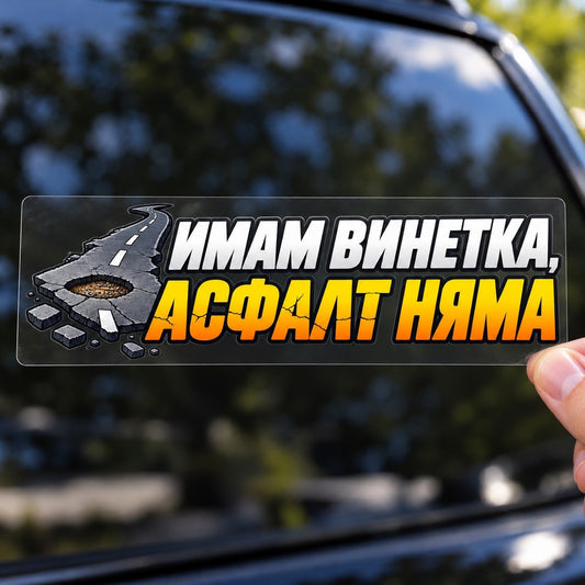 Ръка държи стикер „Имам винетка, асфалт няма“ върху плоско прозрачно транспортно фолио пред автомобил