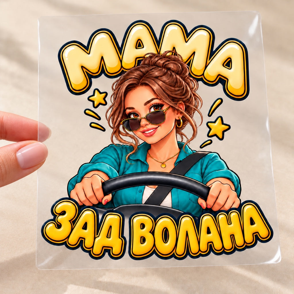 МАМА ЗАД ВОЛАНА - стикер върху транспортно фолио, държан между палец и показалец