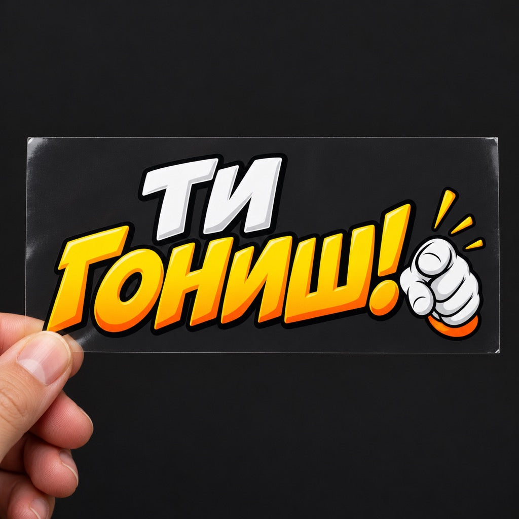 Цветен стикер Ти гониш! върху прозрачно транспортно фолио, държан в ръка